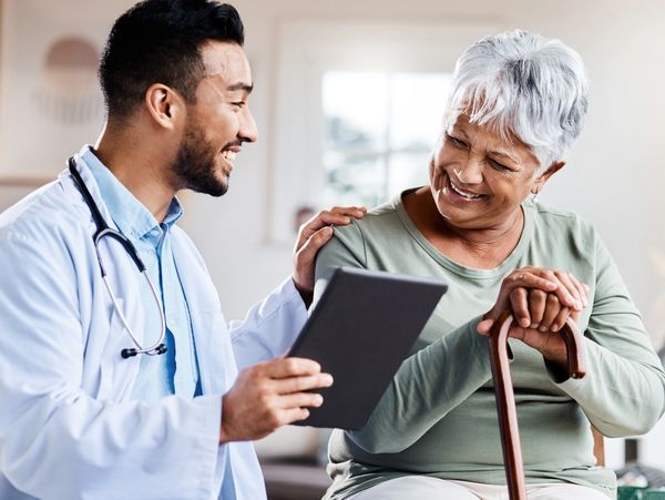 A smiling doctor showing a tablet to a senior woman.