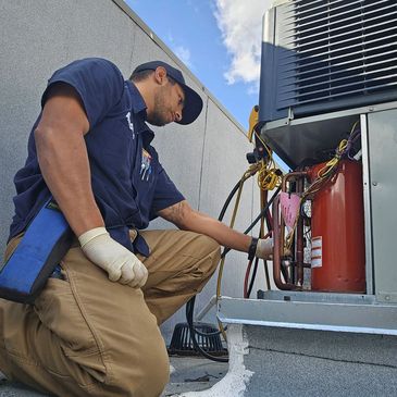 Technician at MIB Associates, Inc. inspecting a rooftop condensing HVAC unit to verify working. 
