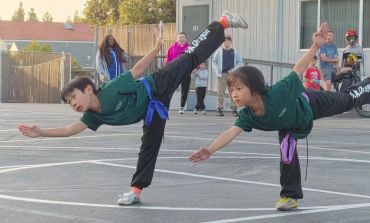 Two kids practicing martial arts outdoors with spectators.