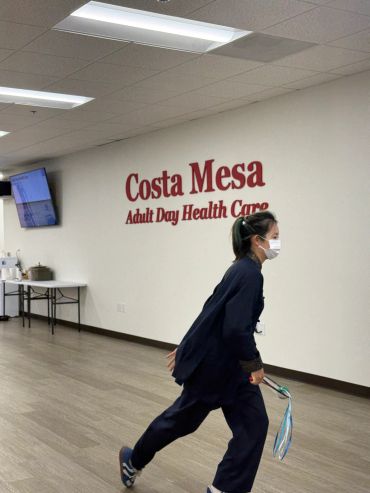 Woman in a mask walking inside Costa Mesa Adult Day Health Care.