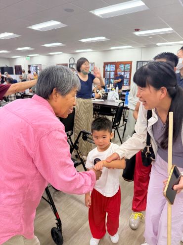 Two women and a boy interact in a lively indoor setting.