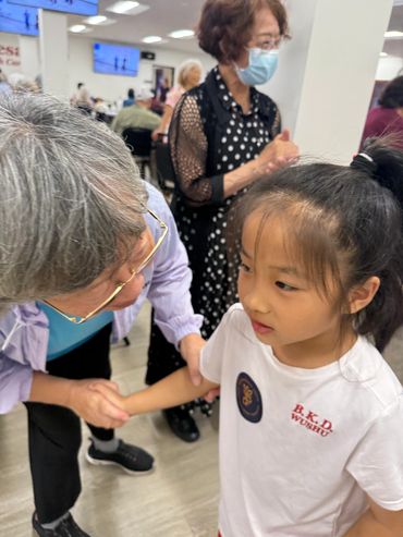 Elderly woman shaking hands with a young girl.
