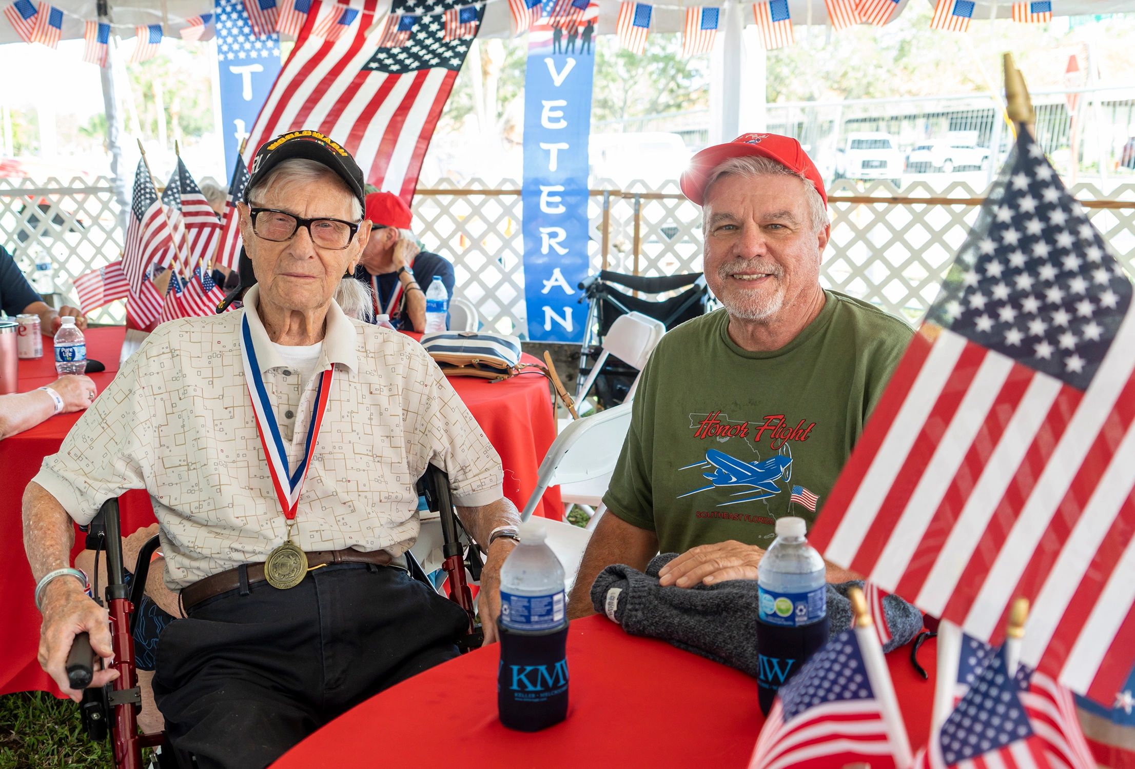 Two men at a patriotic veterans event with American flags around.
