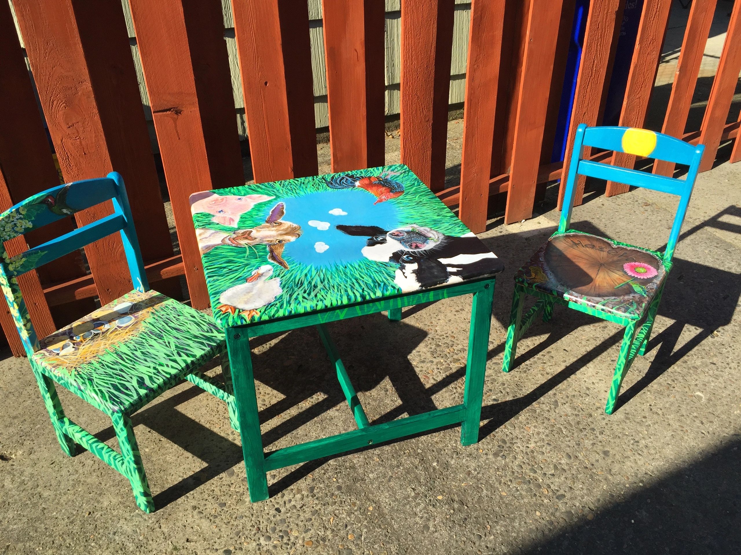 Colorfully painted children's table and chairs with animal and nature designs.