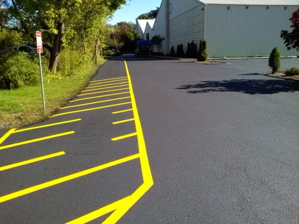 Freshly painted yellow parking lines on a smooth black asphalt surface beside a building.