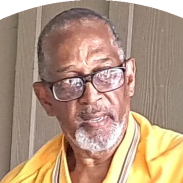 Elderly man with glasses wearing a yellow jacket.