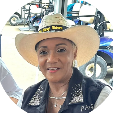 A woman wearing a cowboy hat and a decorated vest smiles at the camera.