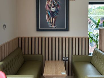 The cafe interior featuring the large Lion painting on the wall. Green comfortable seating.