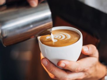 Barista coffee - Barista pouring milk into coffee to make latte art