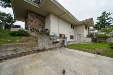 Backyard of a house with a concrete patio and a grassy area.