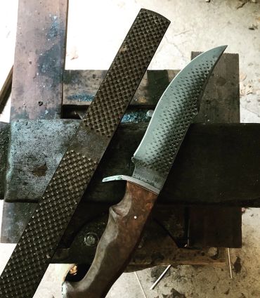 Handcrafted knife and file on a workbench.