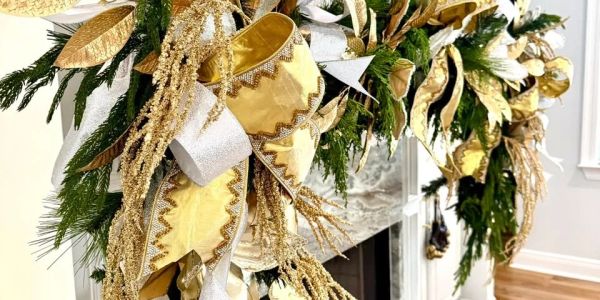 Golden and green holiday garland with ribbons on a mantel.