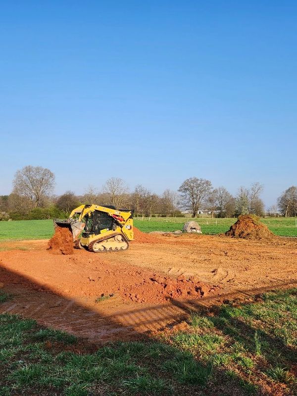 Yellow caterpillar loader moving earth on farmland.