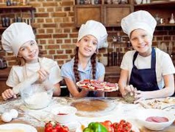 Three children in chef hats baking pizza together in a cozy kitchen.
