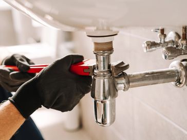 Plumber fixes a sink pipe with a wrench in a bathroom, showcasing precision and craftsmanship
