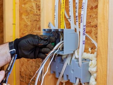 Electrician connects wires inside circuit box while renovating home