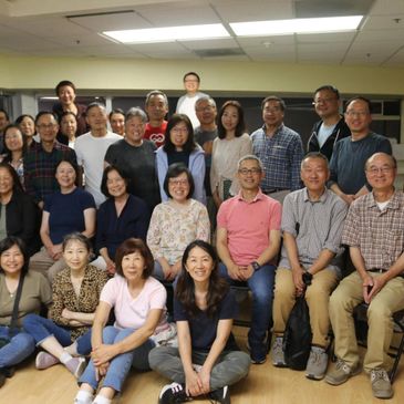 Large group of adults posing together indoors, smiling.