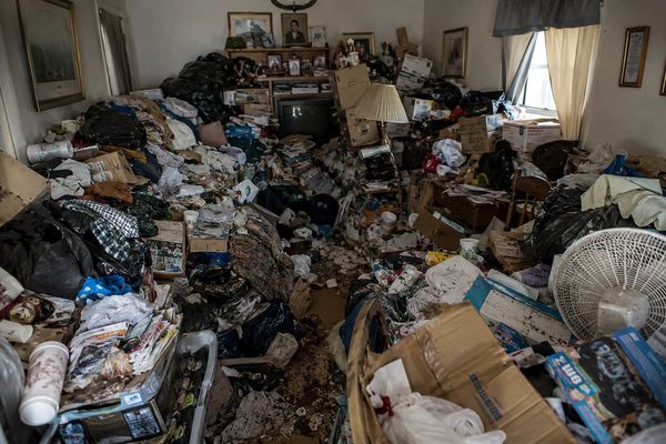 Cluttered living room filled with trash and piles of belongings.