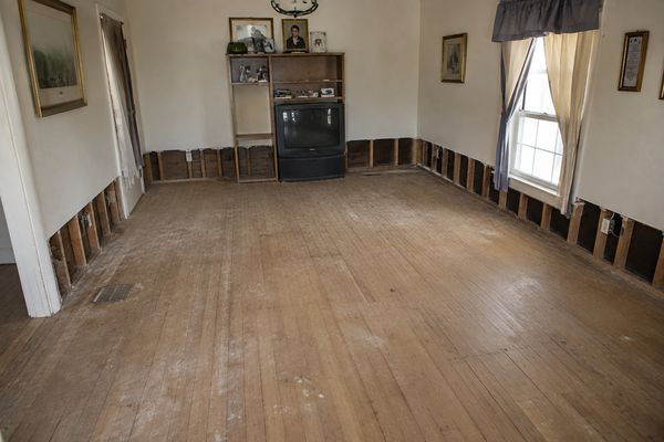 Empty living room with exposed lower walls and wooden floor.