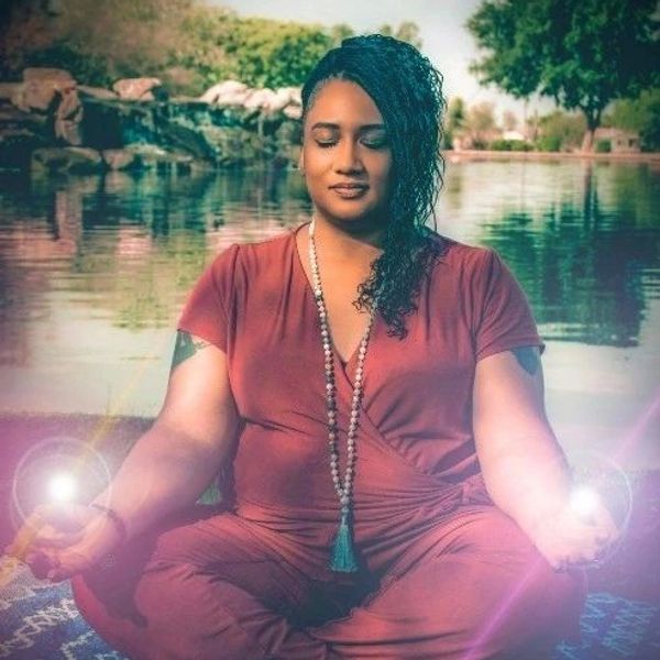Woman meditating by serene water with glowing hands.