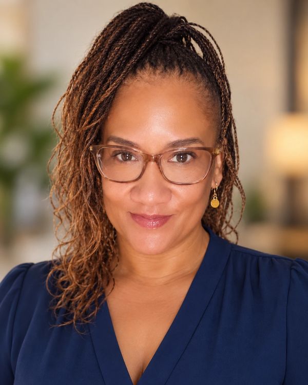 Woman with braided hair wearing glasses and blue top.