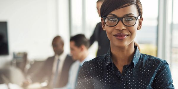 Confident businesswoman with glasses smiling in a modern office.