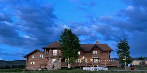 A large wooden house under a cloudy blue evening sky.