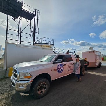 Woman standing next to a white DC Steam pickup truck in an industrial area.