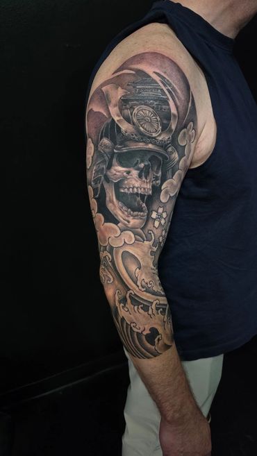 Custom black and grey Japanese-inspired samurai skull tattoo and intricate shading on the upper arm.