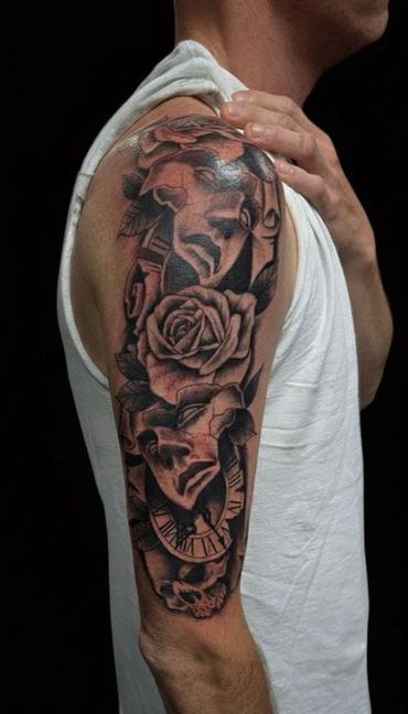 Black & grey realism tattoo featuring drama masks, detailed roses, & pocket watch tattoo
