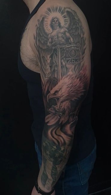 Custom black and grey realism tattoo featuring a guardian angel with outspread wings holding a sword