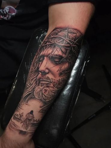 Custom black and grey realism forearm tattoo depicting Jesus Christ wearing a crown of thorns