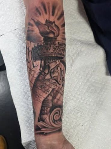 Statue of Liberty torch forearm tattoo in black and grey at Mayhem Tattoo in Salem, NH