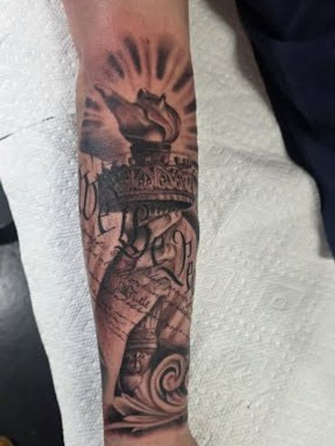 Statue of Liberty tattoo, black and grey realism style on forearm