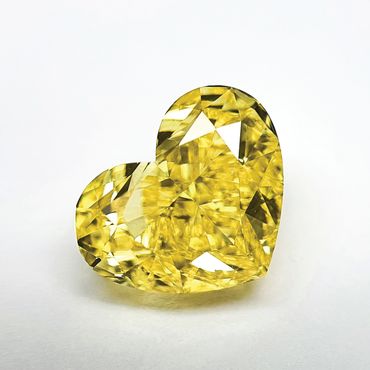 Heart-shaped yellow diamond sparkling on a white surface.