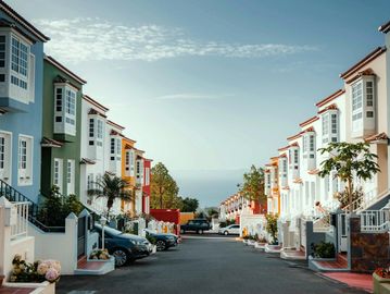 A street lined with colorful two-story houses on a clear day.