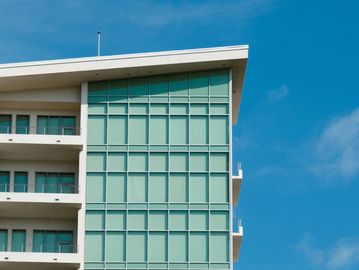 Modern building facade with glass windows against a blue sky.
