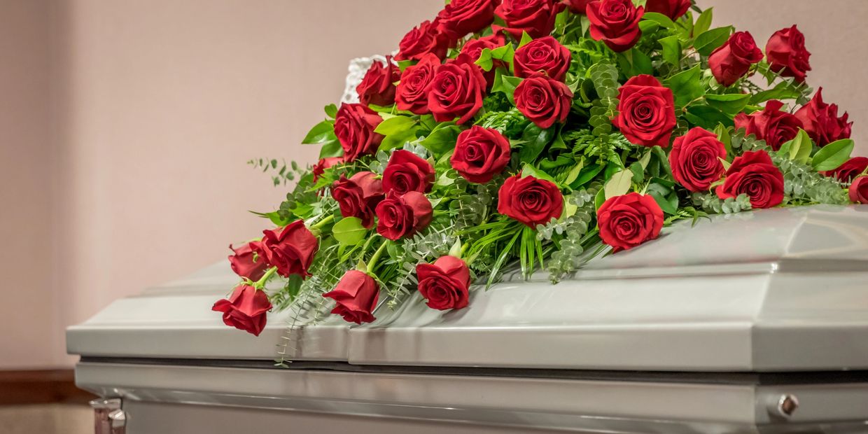 Silver casket with a large red rose arrangement on top.