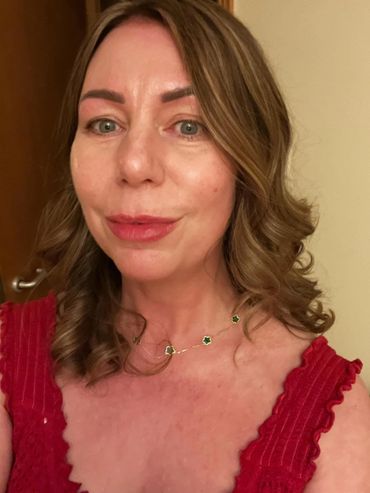 Woman in a red dress with curled hair and a delicate necklace.