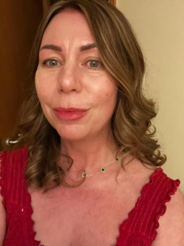 Woman in a red dress with curled hair and a delicate necklace.