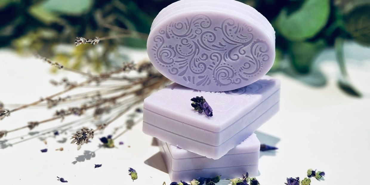 Lavender-scented soaps with intricate designs, surrounded by dried lavender flowers.