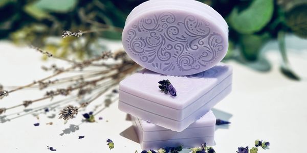 Lavender-scented soaps with intricate designs, surrounded by dried lavender flowers.