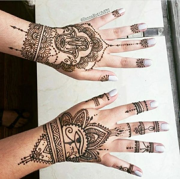 Intricate henna designs featuring Hamsa and eye motifs on both hands.