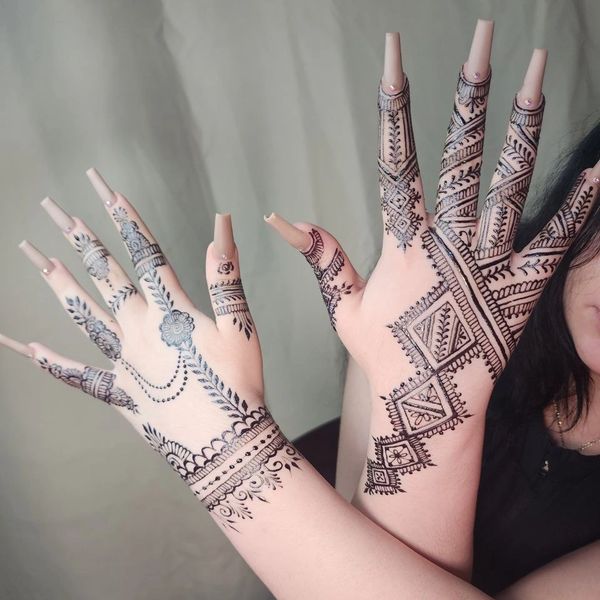 Intricate mehndi designs adorn both hands with long nails and delicate patterns.