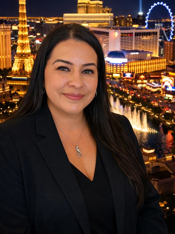 Confident woman in black blazer with Las Vegas night skyline behind her.