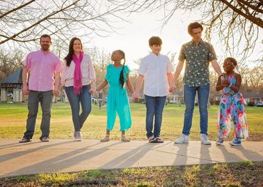 Happy family holding hands outdoors in a park during sunset.