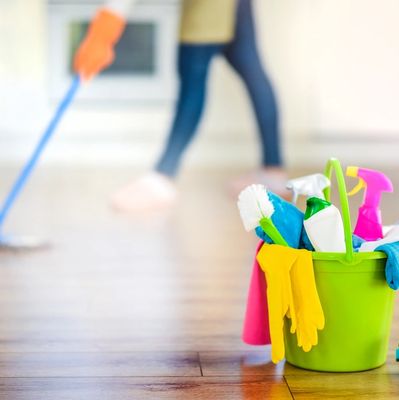 bucket with cleaning products in the foreground of somebody cleaning floors