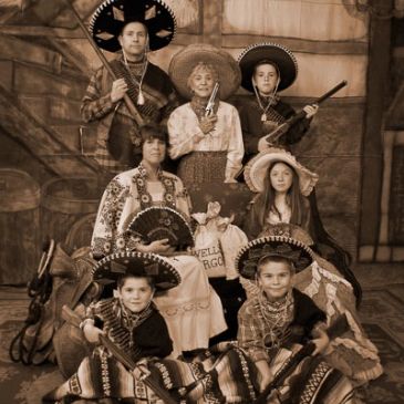 Vintage sepia photo of a family in traditional Mexican attire with sombreros and rifles.
