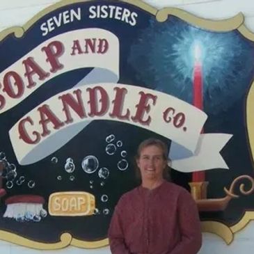 Woman standing in front of a soap and candle company sign.