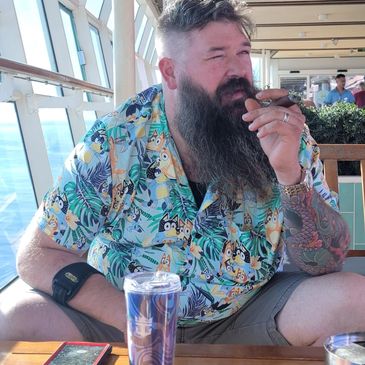 Man with a long beard smoking a cigar on a boat deck.